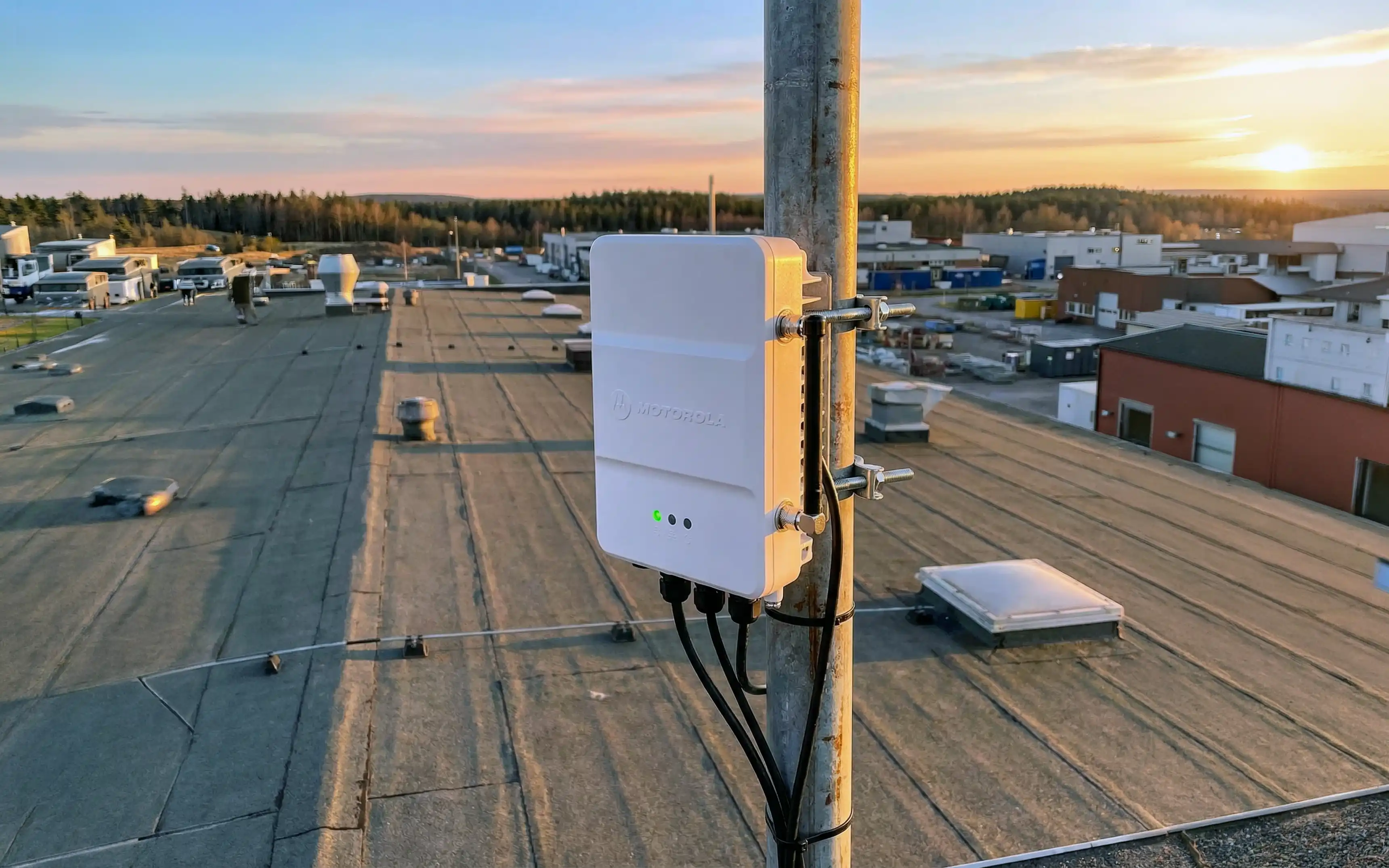 Bild tagen på taket på en industrifastighet som visar en Motorola SLR1000 repeater installerad på en antennstolpe.