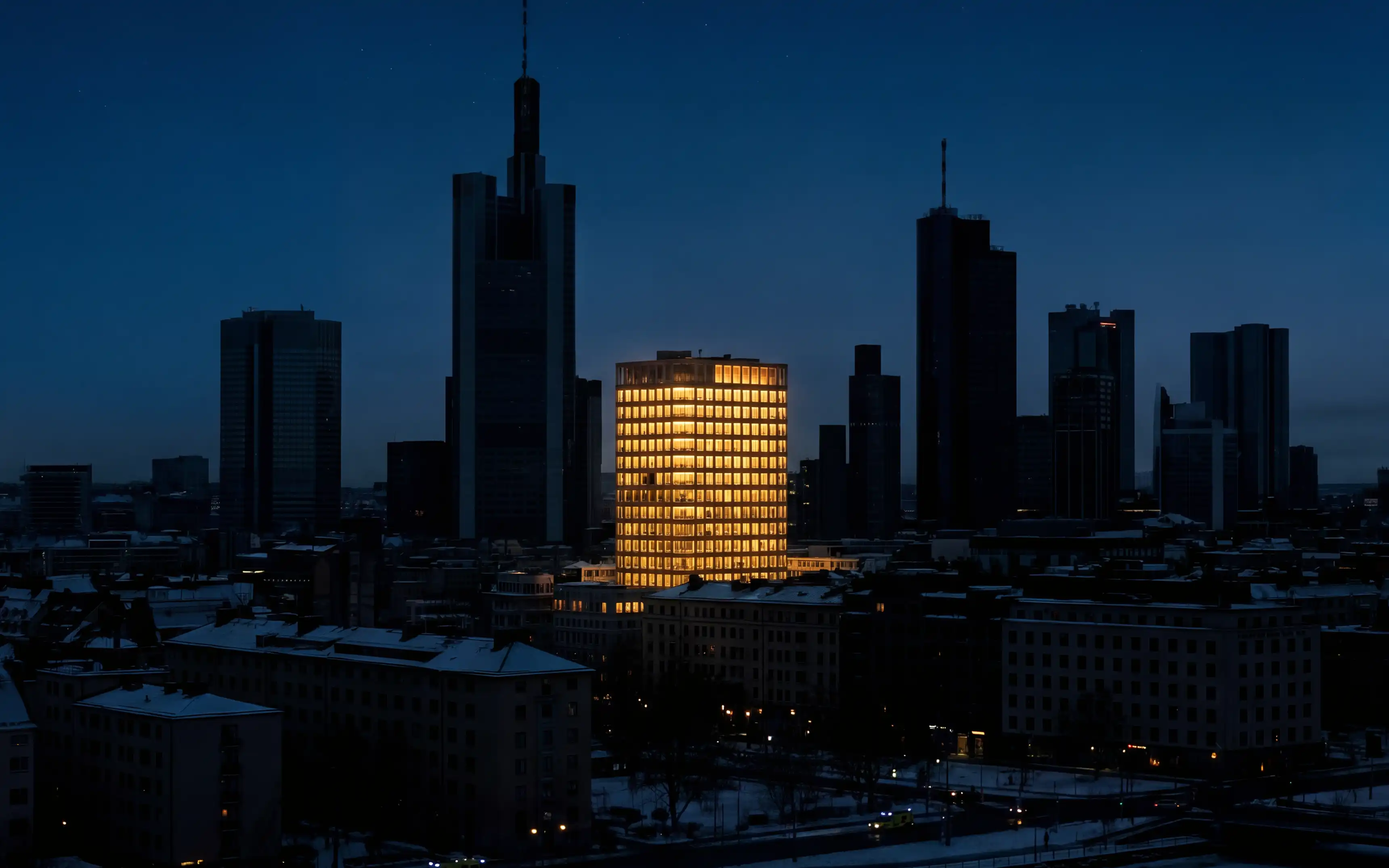 Bild föreställande en siluett av en stad strax efter solnedgång. Mitt i bilden står en byggnad med fullt fungerande belysning under ett stort strömavbrott.